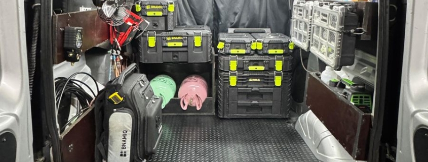 Ferramentas e instrumentos no porta-malas de um veículo, organizados em caixas e bolsas para assistência técnica